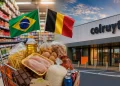 Carrinho de compras em supermercado Colruyt na Bélgica com bandeiras do Brasil e da Bélgica, ilustrando comparação de preços entre os dois países.