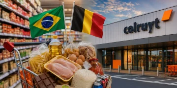 Carrinho de compras em supermercado Colruyt na Bélgica com bandeiras do Brasil e da Bélgica, ilustrando comparação de preços entre os dois países.