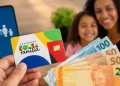 Cartão do Bolsa Família ao lado de cédulas de real e celular, representando a consulta do pagamento do benefício de agosto.