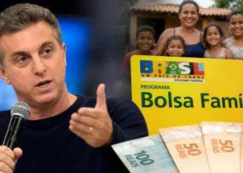 Luciano Huck durante evento ao lado de representação do Bolsa Família e de uma família beneficiária, em imagem que ilustra debate sobre declarações do apresentador e estudos sobre permanência no programa social.